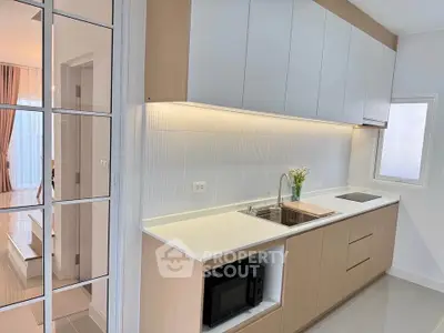 Modern kitchen with sleek cabinetry and built-in microwave in a bright apartment.