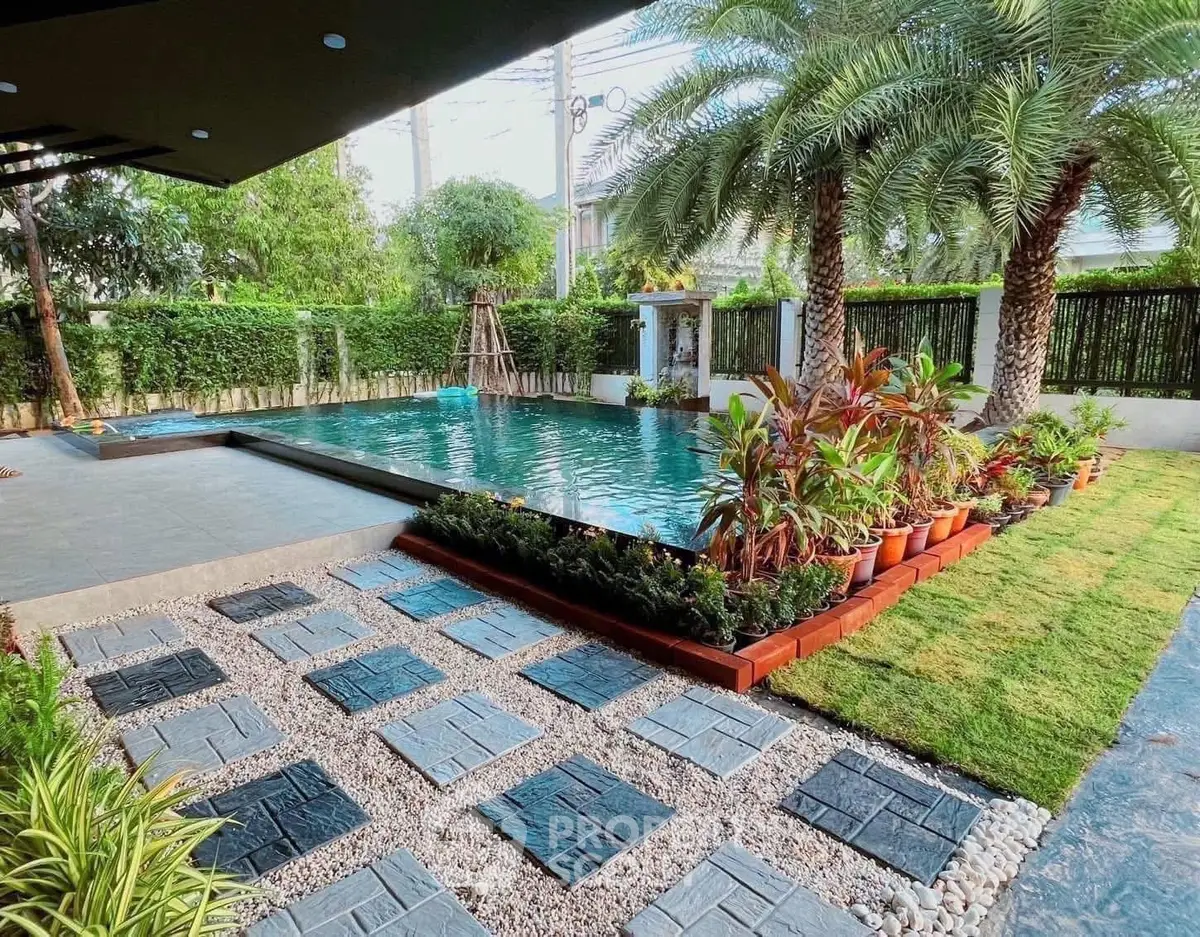 Luxurious garden with pool and lush greenery in modern real estate property.