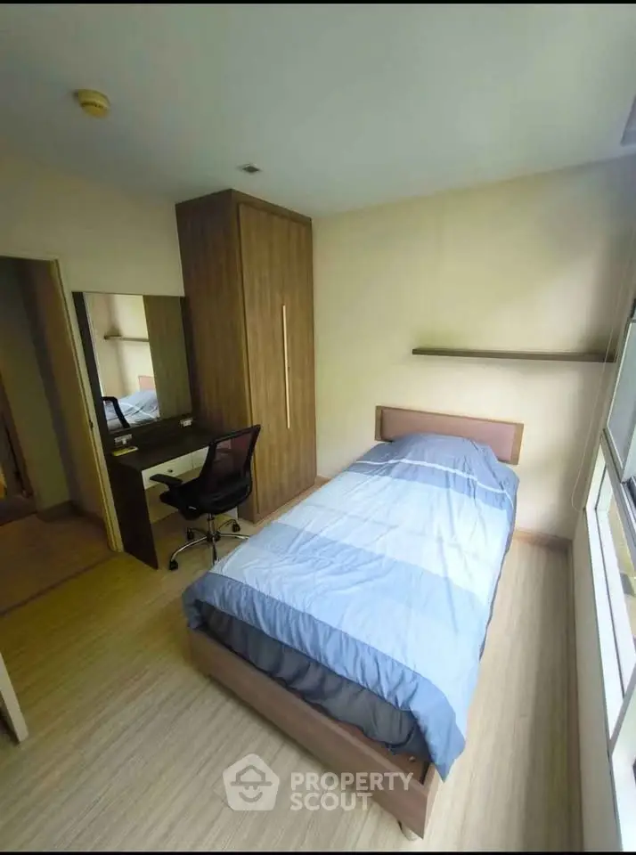 Cozy bedroom with single bed, wooden wardrobe, and study desk in modern apartment.