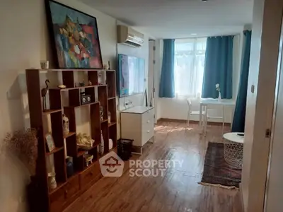 Charming living room with wooden flooring, stylish decor, and ample natural light from large windows.