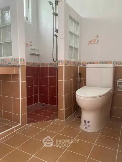 Charming bathroom with tiled shower and modern toilet in cozy home.