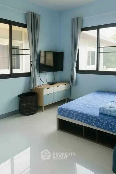 Bright bedroom with large windows, modern TV setup, and stylish decor in a cozy home.