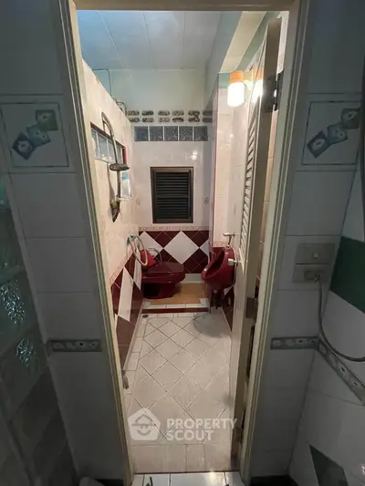 Charming vintage bathroom with unique red fixtures and tiled walls, perfect for a retro-inspired home.