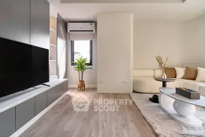 Modern living room with sleek furniture and stylish decor, featuring a large TV and cozy seating area.