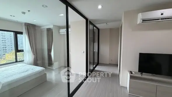 Modern bedroom with glass partition and city view, featuring sleek design and natural light.