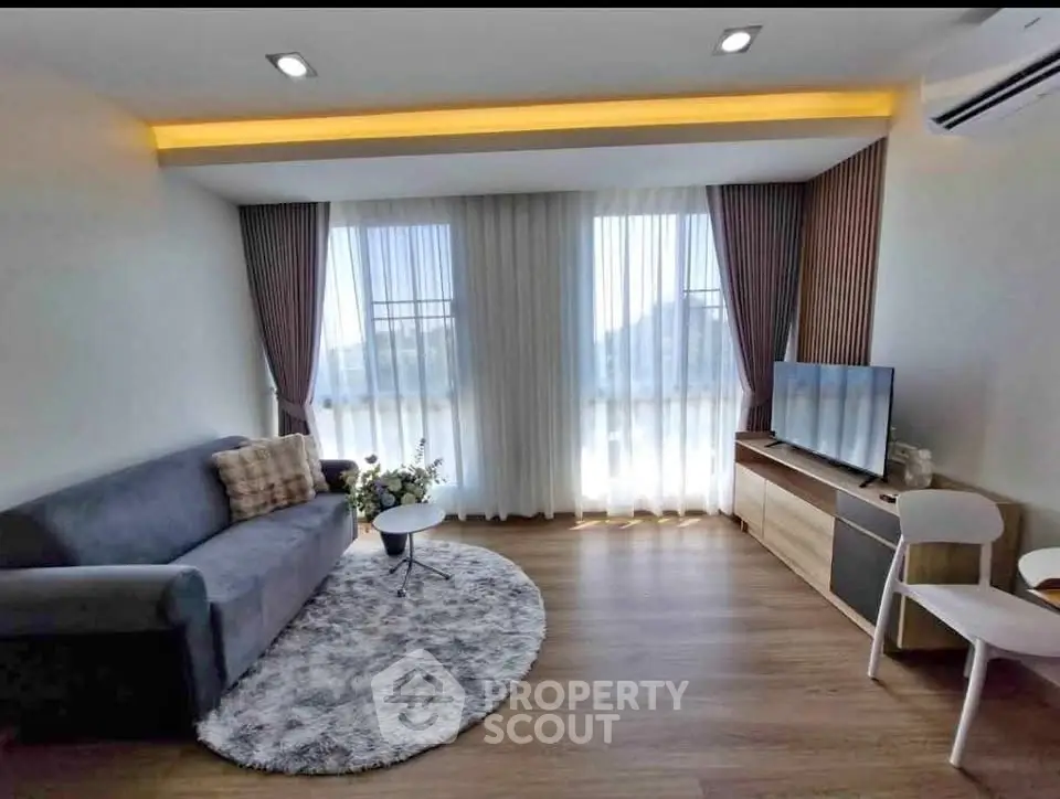 Modern living room with stylish decor, cozy sofa, and large windows offering natural light.