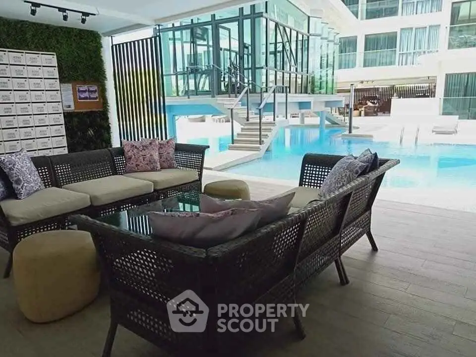 Luxurious poolside lounge with modern seating and glass-walled building view.