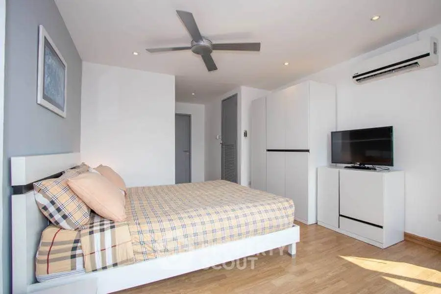 Modern bedroom with stylish decor, ceiling fan, and air conditioning unit.