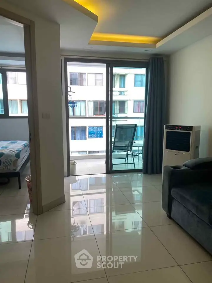 Modern apartment interior with balcony view, sleek tiled floors, and cozy furnishings.