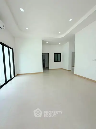 Spacious modern living room with large windows and elegant ceiling design.