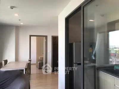 Modern apartment interior with open layout, featuring a dining area and a glimpse of the kitchen and living space.