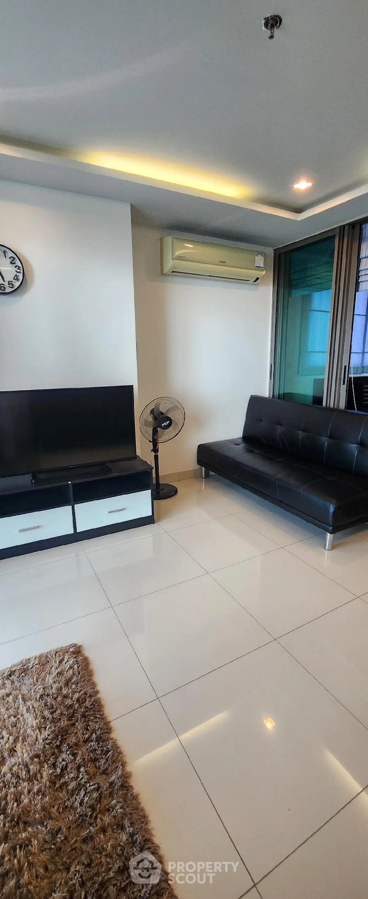 Modern living room with sleek black sofa and large TV in a stylish apartment.
