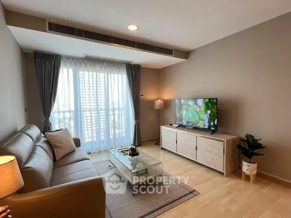 Modern living room with cozy sofa, TV, and balcony view.