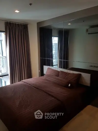 Cozy bedroom with large mirror and elegant brown bedding in modern apartment.