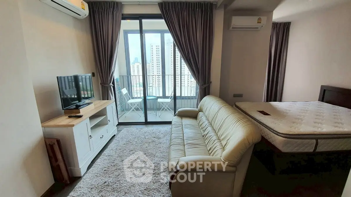 Modern studio apartment with balcony and city view, featuring cozy living area and stylish furnishings.