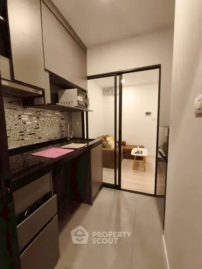 Modern compact kitchen with sleek cabinetry and adjacent cozy living room