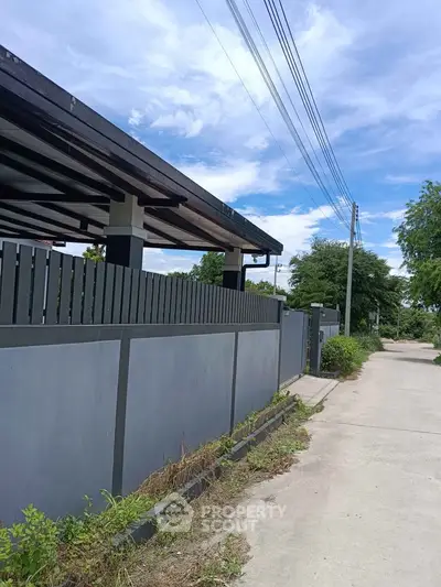 Modern residential property with sleek fence and clear blue sky, showcasing contemporary architecture and serene surroundings.