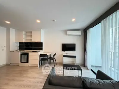 Modern living room with open kitchen, sleek furniture, and large windows for natural light.