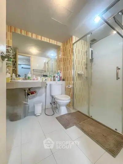Modern bathroom with glass shower and large mirror, featuring sleek tile design.