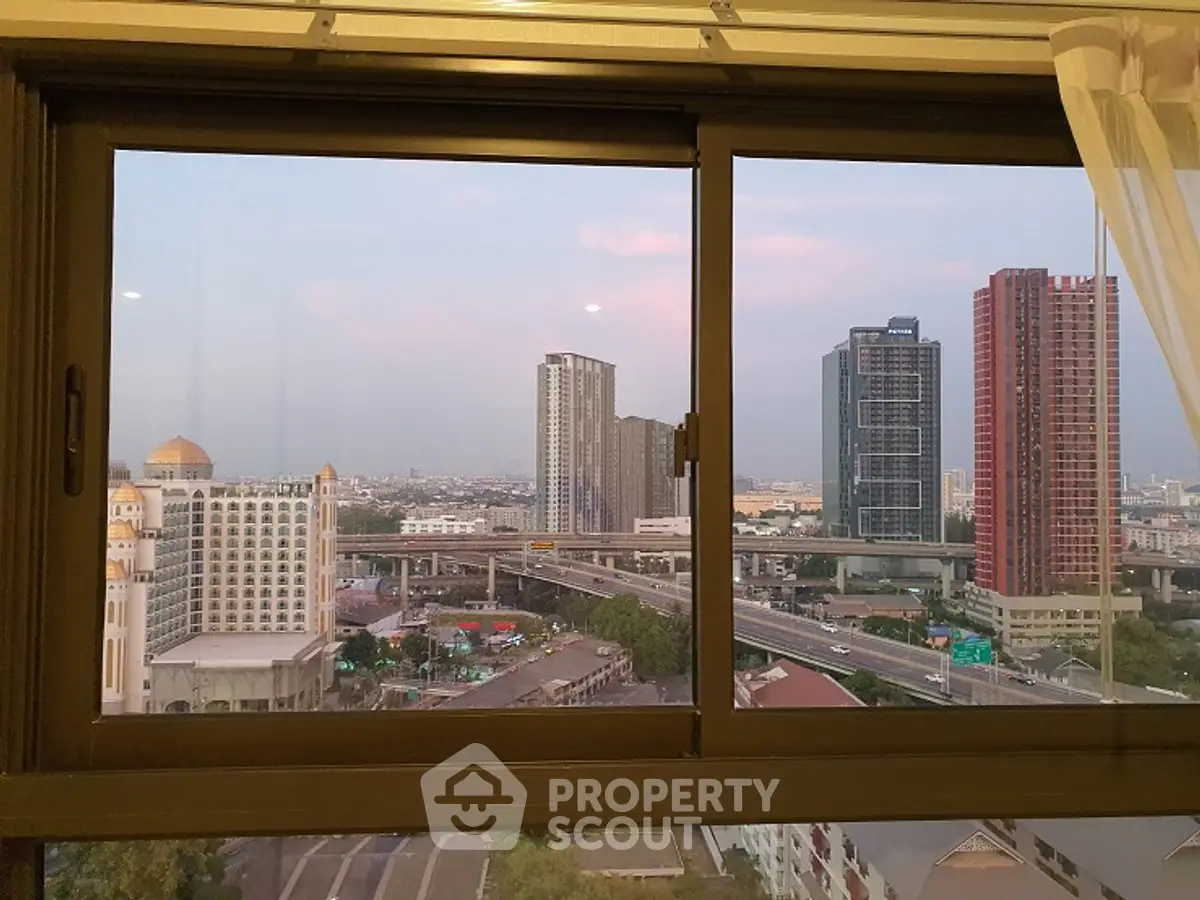 Stunning cityscape view from a high-rise apartment window at sunset.