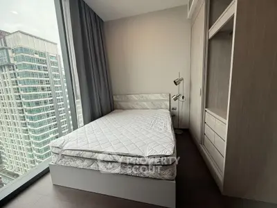 Modern bedroom with floor-to-ceiling windows and city view in high-rise apartment