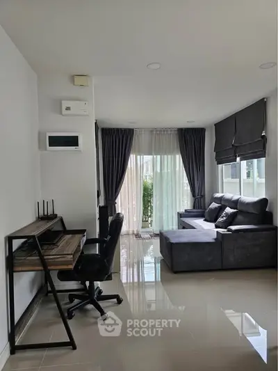 Modern living room with sleek furniture and large windows offering natural light.