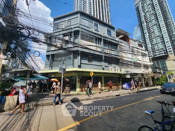 Urban street view with mixed-use buildings and bustling pedestrian activity.