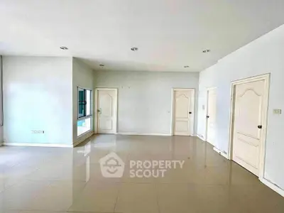 Spacious empty room with glossy tiled floors and multiple doors, ideal for customization.