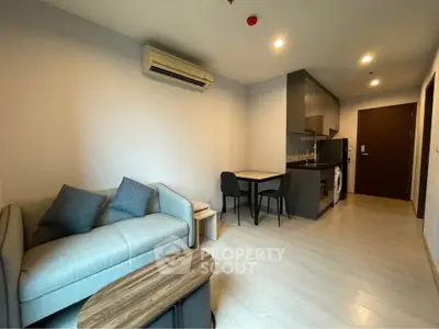 Modern living room with cozy sofa and compact kitchen in open layout apartment.