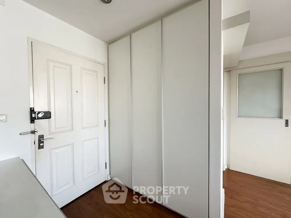 Modern apartment entrance with sleek white doors and wooden flooring