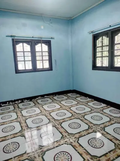 Spacious room with patterned tile flooring and large windows in a serene setting.