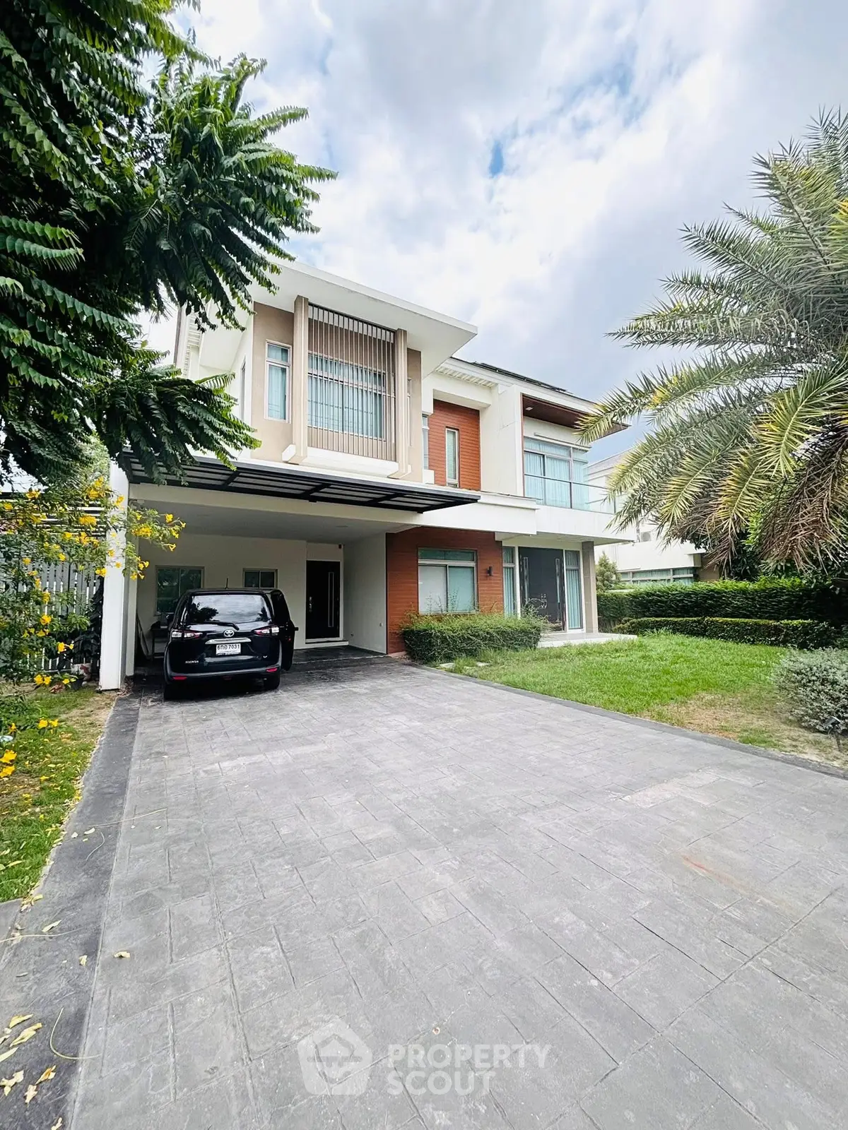 Modern two-story house with spacious driveway and lush greenery, perfect for family living.