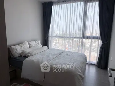 Cozy bedroom with large window offering stunning city views, perfect for relaxation and comfort.