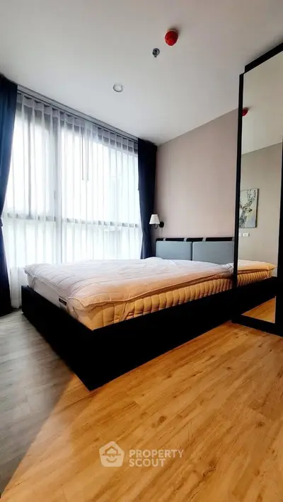 Modern bedroom with large window and stylish decor in a contemporary apartment.