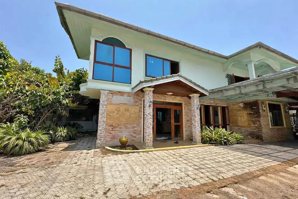 Stunning two-story house with unique architectural design and lush greenery, perfect for luxurious living.