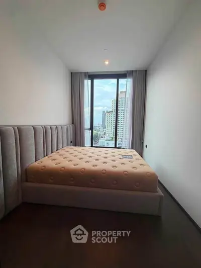 Luxurious bedroom with plush bed and stunning city view from large window.