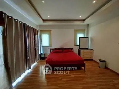 Spacious bedroom with wooden flooring and modern decor in a serene setting.