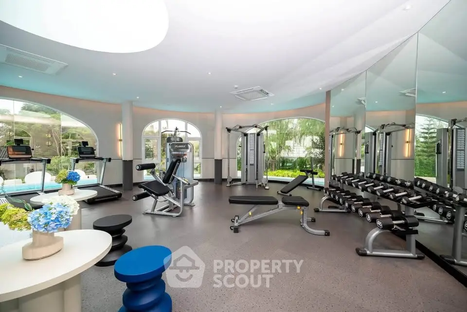 Luxurious gym with modern equipment and large windows offering scenic views, perfect for fitness enthusiasts.