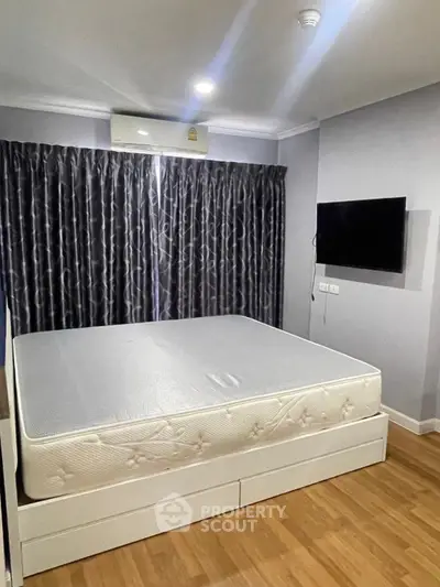 Modern bedroom with large bed, wall-mounted TV, and elegant curtains in a cozy apartment.