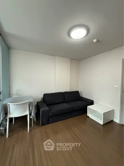 Modern living room with sleek black sofa and wooden flooring, perfect for cozy gatherings.