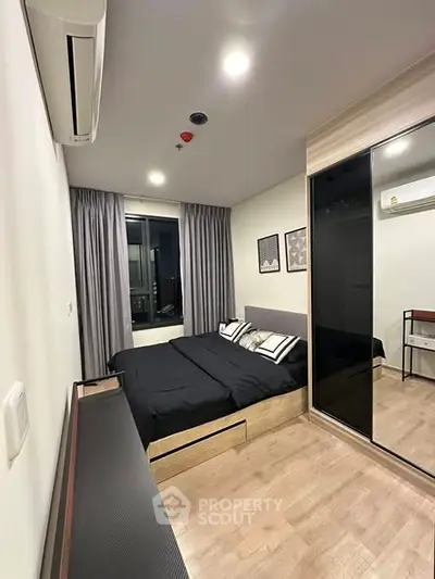 Modern bedroom with sleek design, featuring a large bed, mirrored wardrobe, and air conditioning.