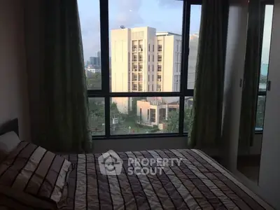 Cozy bedroom with large window offering stunning city view in modern apartment.