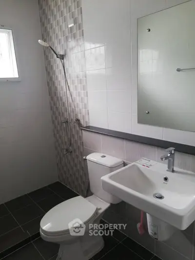 Modern bathroom with sleek fixtures and tiled walls, featuring a shower and white porcelain sink.
