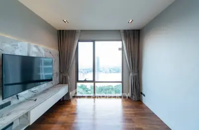 Spacious living room with large window offering stunning city view, featuring modern TV setup and elegant curtains.
