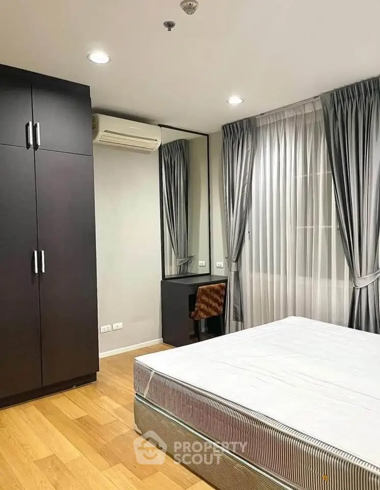 Modern bedroom with wooden flooring, large wardrobe, and stylish curtains.