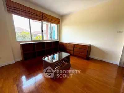 Spacious room with wooden floors and large window, perfect for a cozy living space.