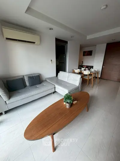 Modern living room with sleek furniture and dining area, featuring neutral tones and stylish decor.
