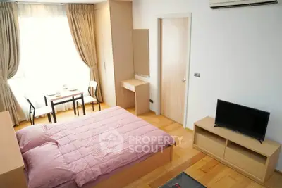 Cozy bedroom with natural light, wooden flooring, and modern furnishings in a stylish apartment.