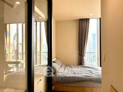 Modern bedroom with city view and balcony access in high-rise apartment