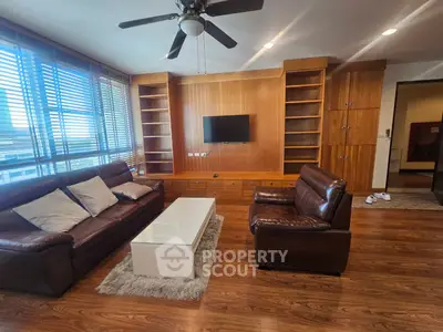 Spacious living room with modern leather sofas and built-in wooden shelves